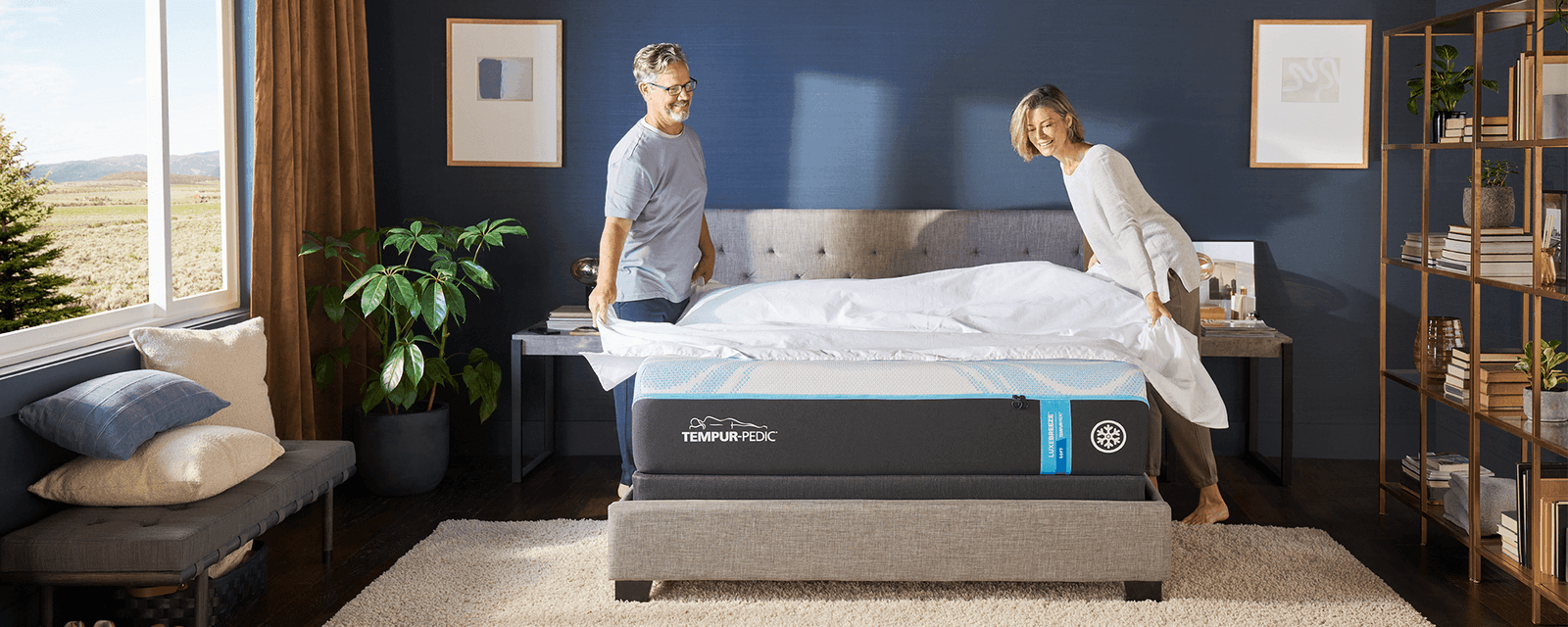 A couple putting sheets on a mattress