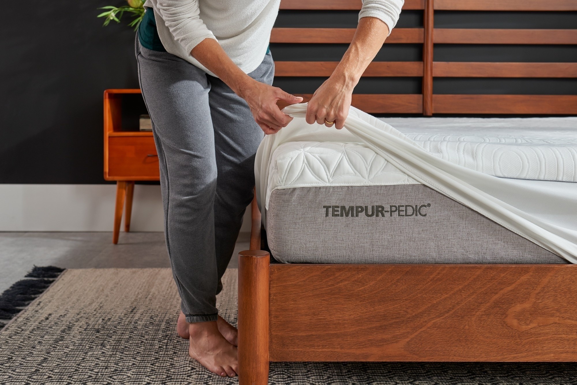 man putting a mattress protector on a bed